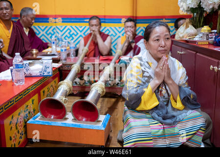 Ein frommer Nepalesischen Sherpa Buddhistischen betet und meditiert vor der Mönche spielen Der dungchen, die traditionelle buddhistische lange Horn. In Elmhurst Queens, NY Stockfoto