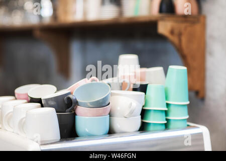 Haufen verschiedene Blau, Rosa, Weiß und Grün cups auf Kaffeemaschine im Cafe. Barista Konzept. Hintergrund der trendy hipster Cafe. Stockfoto