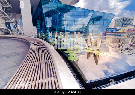 Singapur - Mar 26, 2013: Sky Reflexion in den Teich mit Blumen, Museum der Bildenden Künste futuristischen Blick auf städtische Landschaft mit modernen Wolkenkratzern. Marina Stockfoto