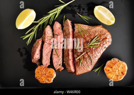 Steak medium Rindfleisch mit Gewürzen auf dunklem Hintergrund, Ansicht von oben Stockfoto