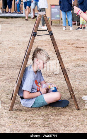 Junge findet kreative Art und Weise zum Schutz vor Regen, Latitude Festival, henham Park, Suffolk, Großbritannien am 20. Juli 2019 Stockfoto