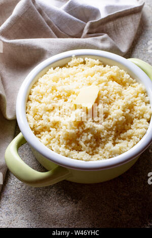 Couscous mit Butter im Topf auf hellen Hintergrund Stockfoto