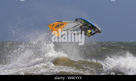 Ein Windsurfer stürzt durch die Wellen bei windigen Bedingungen im Camber, East Sussex. Stockfoto