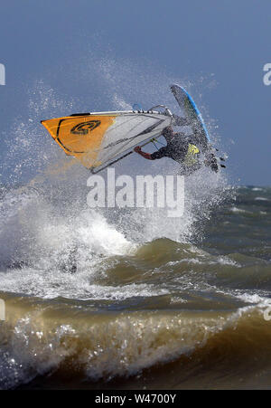 Ein Windsurfer stürzt durch die Wellen bei windigen Bedingungen im Camber, East Sussex. Stockfoto