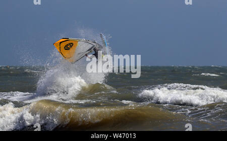 Ein Windsurfer stürzt durch die Wellen bei windigen Bedingungen im Camber, East Sussex. Stockfoto