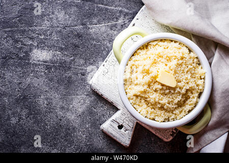 Couscous mit Butter im Topf auf dunklem Hintergrund Stockfoto