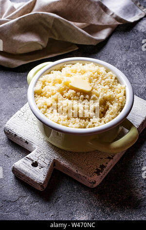 Couscous mit Butter im Topf auf dunklem Hintergrund Stockfoto