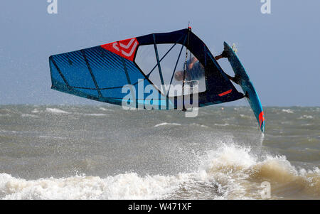 Ein Windsurfer stürzt durch die Wellen bei windigen Bedingungen im Camber, East Sussex. Stockfoto