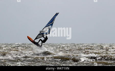 Ein Windsurfer stürzt durch die Wellen bei windigen Bedingungen im Camber, East Sussex. Stockfoto