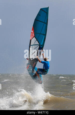 Ein Windsurfer stürzt durch die Wellen bei windigen Bedingungen im Camber, East Sussex. Stockfoto