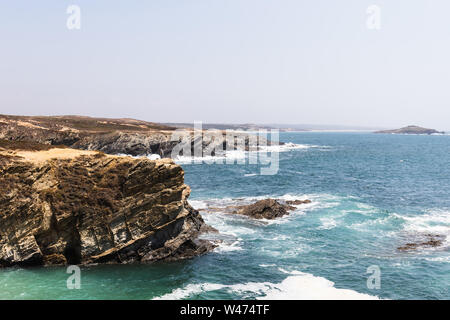 Ein unbekannter Mann steht in der Nähe einer Klippe mit Blick auf das Meer in der Ortschaft Porto Covo, Portugal Stockfoto