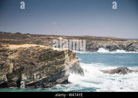 Ein unbekannter Mann steht in der Nähe einer Klippe mit Blick auf das Meer in der Ortschaft Porto Covo, Portugal Stockfoto