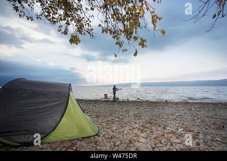 Mann im Camp in der Nähe von See, Angeln Stockfoto