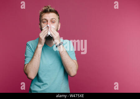 Studio Bild von einem jungen Mann mit Taschentuch. Kranken Kerl isoliert hat Schnupfen. Man macht eine Heilung für die allgemeine Kälte Stockfoto