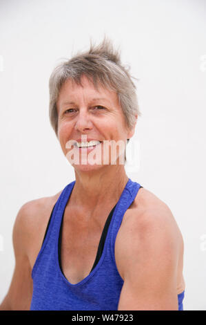 Reifer senior Frau üben Sanfte restorative Yoga Posen lächelnd Portrait in weißem Hintergrund fotografiert. Stockfoto