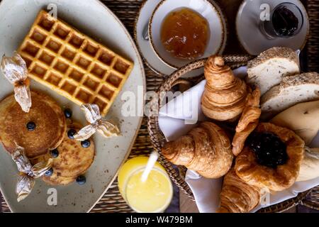 High-Angle-Schuss von einem Pfannkuchen und Waffel in einem Runder Teller in der Nähe des trey mit Croissant Stockfoto