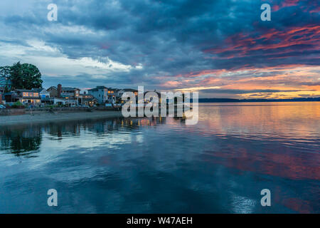 Die Wolken hängen am Himmel, wie die Sonne hinter den Olympic Mountains im Armaturenbrett, Washington. Stockfoto