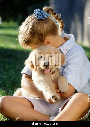 Junge Mädchen mit einem Golden Retriever Welpe Stockfoto