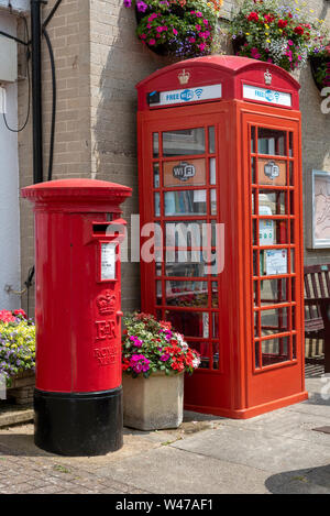 Bier, Devon, England, UK. Juli 2019. Ein Royal Mail postbox und ein ehemaliger Telefon Box verwendet als Buch Bibliothek und WiFi Station sowohl neu lackiert b Stockfoto