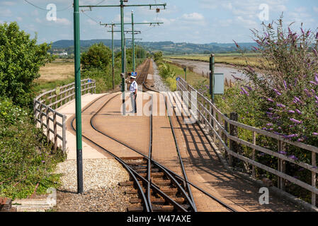 Seaton, Devon, England, UK. Juni 2019. Eine Straßenbahn Mitarbeiter am Flußufer Depot stop entlang des Flusses Axe in East Devon. Stockfoto