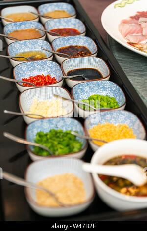 Vertikale Aufnahme von Gewürzen und Sauce in verschiedenen Schüsseln Stockfoto