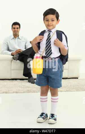 Porträt eines Schuljungen, die Schultasche mit seinem Vater im Hintergrund Stockfoto