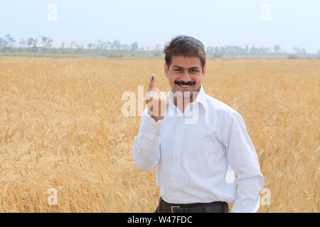 Porträt eines Geschäftsmannes, der auf einem Feld nach oben zeigt Stockfoto