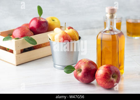 Gesunde Bio-lebensmittel. Apfelessig oder Saft im Glas Flasche und Frische rote Äpfel auf einem hellen Hintergrund. Stockfoto
