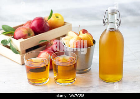 Gesunde Bio-lebensmittel. Apfelessig oder Saft im Glas Flasche und Frische rote Äpfel auf einem hellen Hintergrund. Stockfoto
