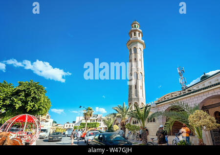 Stadtbild mit Einkaufsstraße und hohen Minarett der Moschee in der Altstadt. Nabeul, Tunesien, Nordafrika Stockfoto