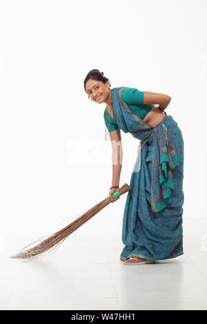 Frau fegt, und lächelnd Stockfoto