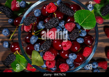 Sommer, reife Beeren in einer transparenten Schüssel auf einem dunklen Hintergrund Stockfoto