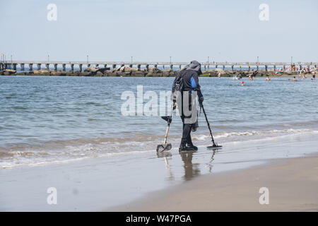 Mann Spaziergänge am Strand mit einem Metalldetektor am frühen Morgen auf Coney Island suchen Schätze im Sand vergraben. Brooklyn, NY. Stockfoto