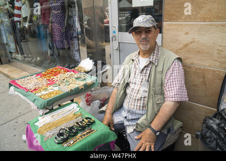 Mann verkauft Halsketten und Armbänder vor einem women clothing Store zusammen Kirche Avenue in Brooklyn, New York. Stockfoto