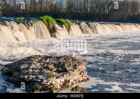 Venta rapid im Frühjahr mit einer Felsformation im Vordergrund. Kuldiga, Lettland. Stockfoto