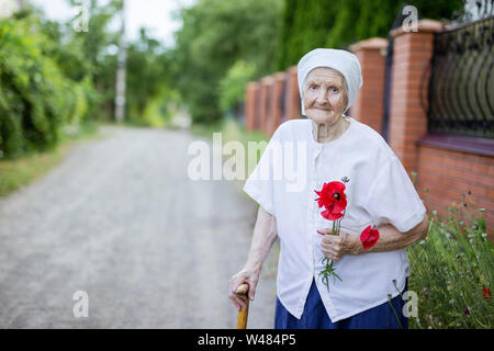 Portrait der älteren Frau mit Mohn Blumen im Freien Stockfoto