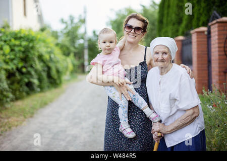 Familie mit drei Generationen stehen draußen in der Landschaft: ältere Frau, ihre erwachsenen Enkelin und Urenkelin Kleinkind Stockfoto