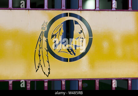 Landover, Maryland, USA. 30. Juni, 2019. Ausschnitt der Washington Redskins Indische Kopf mit Unterkante feather Logo auf Metall Tür an der Bank von Amerika Gate E-für Loge, Suite, und Behinderte/Behinderte/anders als Abled Gäste - bei FedEx Field, Heimstadion der National Football League (NFL) kontrovers namens American Football Team. Im Juli 2019 wurde berichtet, dass die 32 Teams in der Liga, ebenso von $ 8,78 Mrd. in der nationalen Einnahmen für das vergangene Jahr geteilt. Kay Howell/Alamy Stockfoto