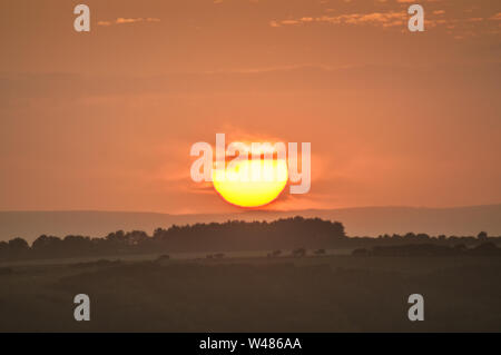 Eastbourne, East Sussex, Großbritannien. Juli 2019..Glorious Sunset Sequence over the misty countryside as Sun dips behind Cloud to reerscheint Minuten später on Horizon. Zwei Sonnenuntergänge an einem Tag. . Stockfoto