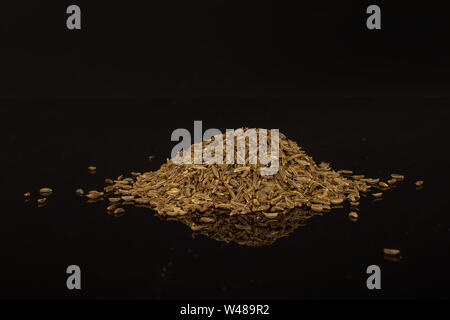 Menge ganze trocknen Kümmel Früchte heap auf schwarzem Glas isoliert Stockfoto
