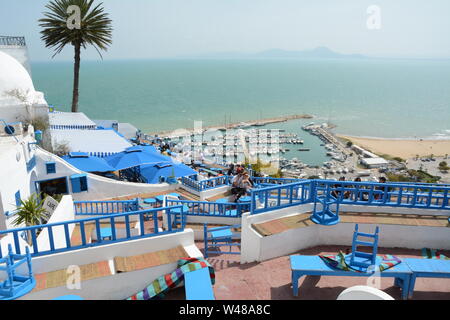 Ein junges Paar Tunsian sitzen in einem Café, Tisch mit Blick auf den azurblauen Mittelmeer und Hafen in der Stadt von Sidi Bou Said, Tunis, Tunesien. Stockfoto