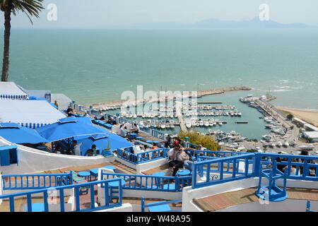 Ein junges Paar Tunsian sitzen in einem Café, Tisch mit Blick auf den azurblauen Mittelmeer und Hafen in der Stadt von Sidi Bou Said, Tunis, Tunesien. Stockfoto