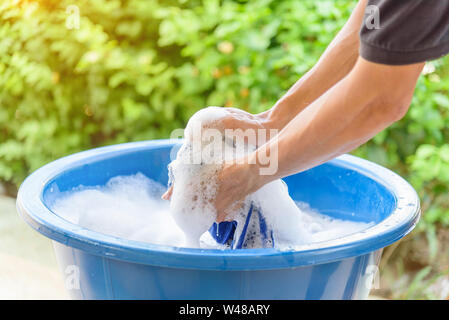 Hände waschen Kleidung in blauen Becken Stockfoto