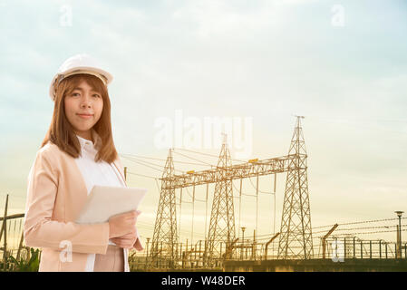 Smart junge schöne Elektroingenieur Frau arbeiten mit Tablet für die Kontrolle der Stromnetze an elektrischen Werk. Stockfoto