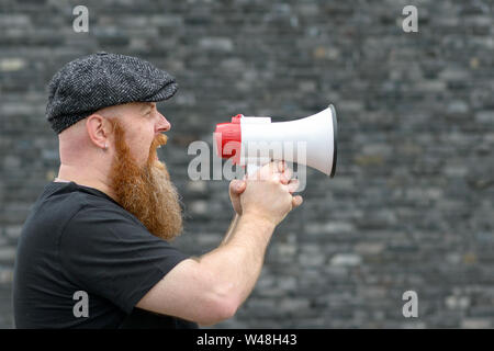 In der Nähe eines grossen Mann in ein Megaphon auf einer Kundgebung oder Streik in einem Kommunikationskonzept schreien Stockfoto