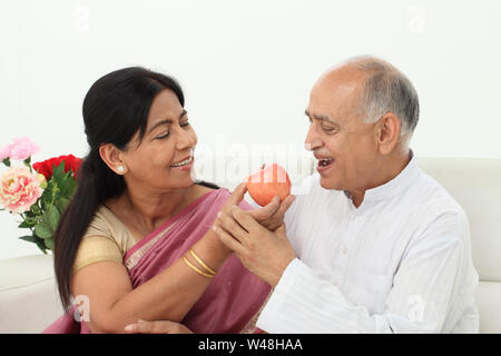 Ältere Frau füttert ihrem Mann einen Apfel Stockfoto