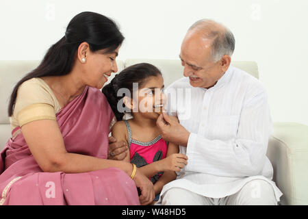 Seniorenpaar, die ihrer Enkelin Keks füttern Stockfoto