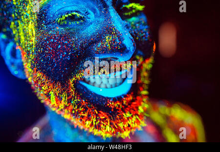 Konzept. Ein bärtiger Mann lächelt. Portrait eines bärtigen Mann in fluoreszierendem Pulver gemalt. Stockfoto