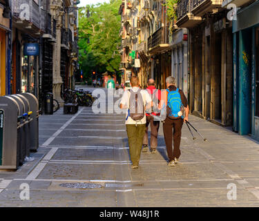 Navarra, Spanien: Pilger zu Fuß auf dem Camino de Santiago. Drei Wanderer mit Kleinpackungen durch die sonnigen Morgen Straßen von Pamplona verlassen Stockfoto