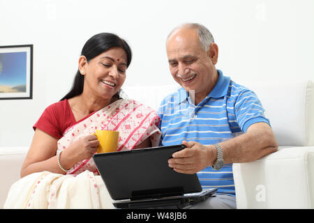 Älterer Mann, der mit seiner Frau einen Laptop benutzt Stockfoto